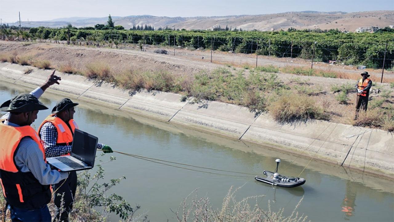 两名水流工程师沿着约旦一条狭窄的河流引导测量装置